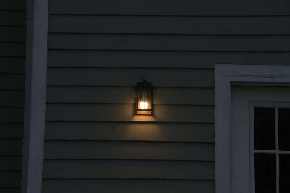 Modern home exterior with motion-activated security lights illuminating driveway at dusk